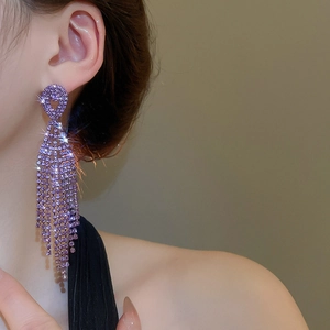 Close-up of elegant purple rhinestone fringe earrings worn by a model in soft light