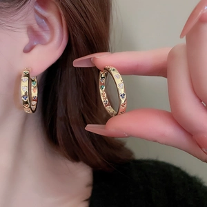 Detailed close-up of golden hoop earrings featuring colorful heart-shaped zirconia stones