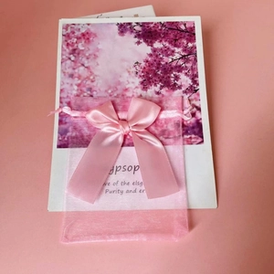 Detailed view of pink organza drawstring gift bag with a decorative satin ribbon bow