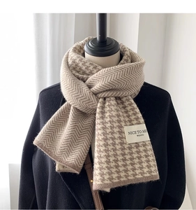 Detail of beige knitted houndstooth scarf showing premium texture and weave patterns