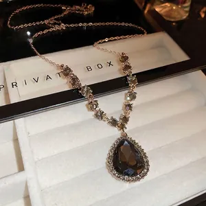 Collier en V luxe or rose avec pendentif goutte gris foncé dans un coffret bijoux