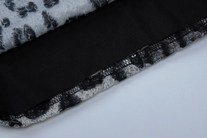 Detail shot of leopard print fabric stitched with black fabric and shiny sequins