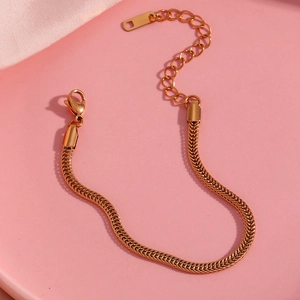 Detailed view of 18K gold plated snake chain bracelet with lobster clasp on pink surface
