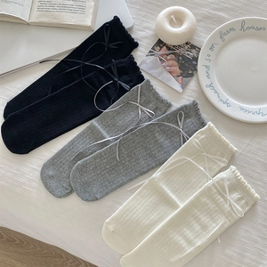 Detailed knit texture of ribbed mid-calf socks with delicate lace trim and ribbon bows