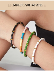 Detail view of chic bamboo-shaped enamel bangles in multiple colors on a model's wrist