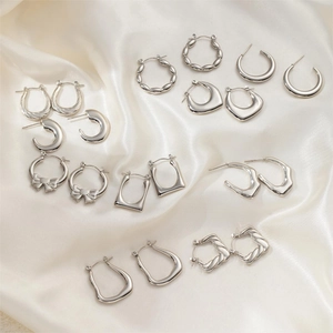 Flat lay of silver stainless steel earrings set featuring bow and geometric designs