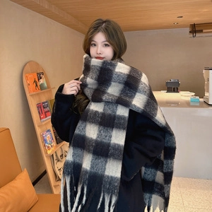 Close-up of black and white plaid scarf with fringe worn by a model in soft light