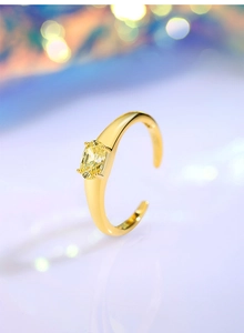 Macro shot of an adjustable gold ring featuring an oval yellow gemstone with claw setting