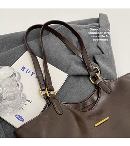 Detail of dark brown tote bag with smooth long shoulder strap and golden metal buckle
