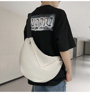 Rear view of a minimalist white crossbody bag worn by a model in a modern indoor setting