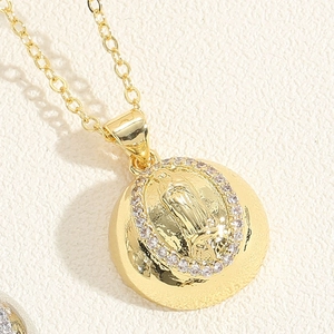 Macro shot of gold Virgin Mary pendant with sparkling white crystals and cross chain