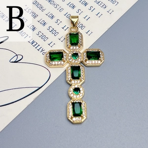 Detail of a gold cross pendant with emerald green zircons and pavé white stones