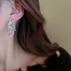 Orecchini a foglia d'argento con nappe in zirconia indossati da una modella donna