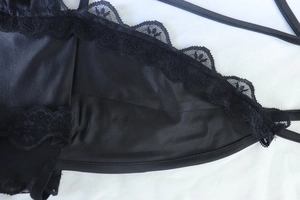 Detail of delicate black lace trim and satin fabric on sexy slit evening dress