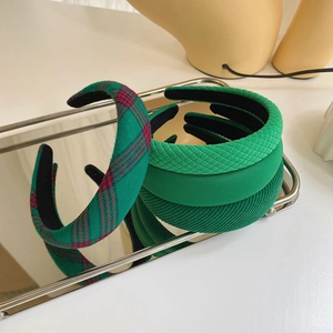 Detailed display of green padded headbands in various textures on a silver tray