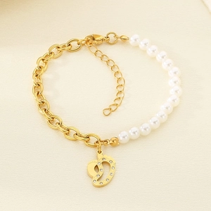 Detail of gold chain and pearl bracelet featuring a crystal footprint pendant charm