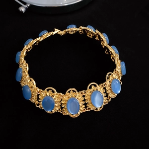 Detail of vintage gold choker with blue oval gemstones and baroque pattern