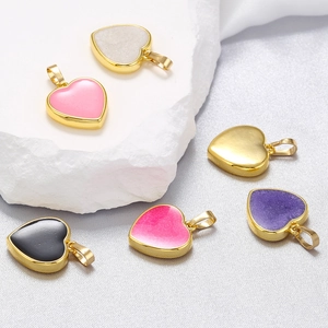 Colorful heart-shaped pendants with 18K gold plating on a stone and fabric background