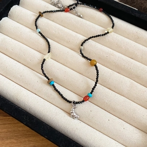 Close-up of beaded necklace with natural stones and a silver bear pendant on velvet