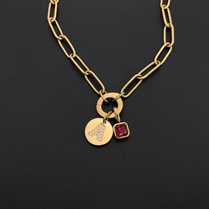 Dettaglio collana a catena dorata con ciondolo lettera A in strass e gemma rossa