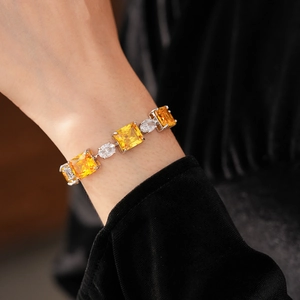 Detail of fashion bracelet with square yellow zircon and oval white stones on wrist