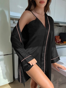 Détail du peignoir en satin noir avec liseré rose contrasté et décolleté en V soyeux
