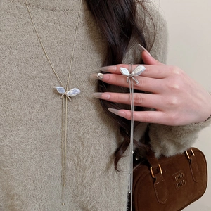 Detail of adjustable butterfly tassel necklace with pearl shell and crystals on knitwear