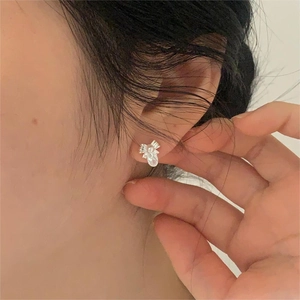 Close-up of 925 sterling silver bow earrings with pearl and zircon on model ear
