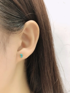 Close-up of V-shaped turquoise stud earrings in gold finish on a model's ear