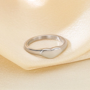 Detailed macro shot of a heart-shaped silver stainless steel signet ring on silk