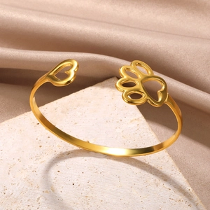 Detailed shot of gold heart and paw print hollowed charms on a geometric open bangle