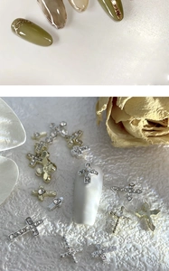 Macro detail of alloy silver and gold 3D cross nail charms with sparkling rhinestones