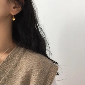 Close-up of elegant gold heart drop earrings worn on a model for a stylish look