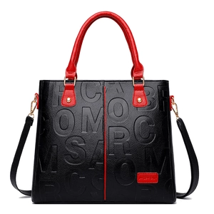 Black embossed faux leather handbag with red handles and detachable shoulder strap