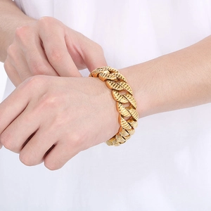 Close-up of thick gold Cuban link chain bracelet with twill texture on male wrist