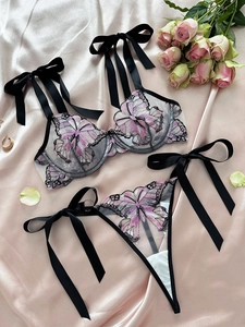 Close-up of butterfly embroidery and satin ribbon bows on sheer mesh lingerie set