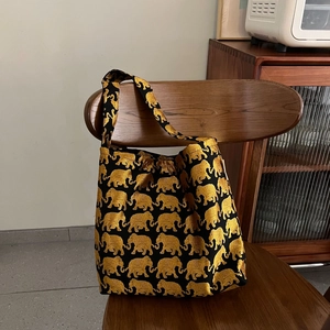Sac fourre-tout en toile noire avec motif d'éléphant doré sur une chaise en bois