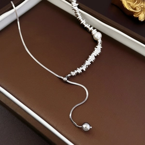 Detail of silver snake chain necklace with irregular silver beads and a white pearl