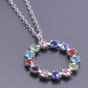 Macro shot of circular stainless steel pendant with multi-colored crystals on a silver chain