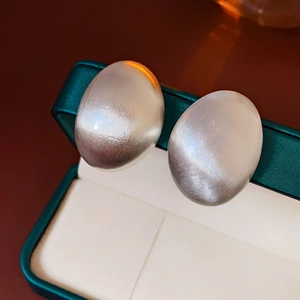 Vue macro de boucles d'oreilles ovales en argent brossé sur une boîte en velours