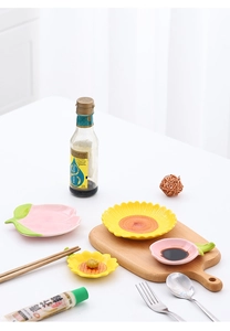 Ceramic sauce dishes in sunflower and peach shapes on a wooden board for table service