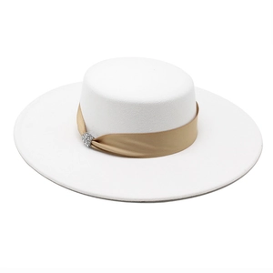 Close-up of white wool boater hat featuring a champagne ribbon and rhinestone buckle