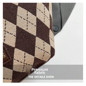 Macro shot of argyle canvas fabric texture with dark brown leather logo detail