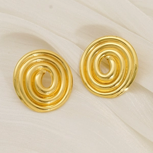 Vue rapprochée de boucles d'oreilles spirales dorées à texture métallique sur du tissu