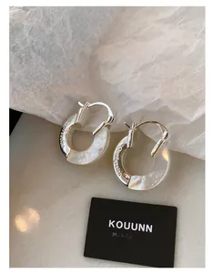 Macro view of silver ear hoops featuring iridescent mother of pearl and Confession engraving