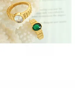 Macro shot of gold-plated U-shaped earrings with inlaid emerald and clear stones