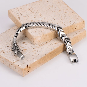 Polished stainless steel snake bone chain bracelet for men on beige travertine stone