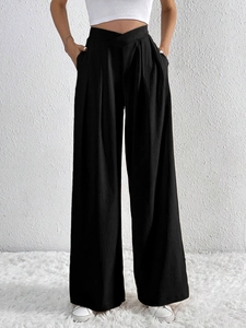 Detail of high-waist black wide-leg trousers featuring a unique V-cross waistband design