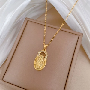 Detailed macro of gold Virgin Mary oval pendant with zircon halo on beige box