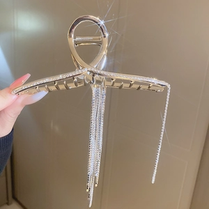 Détail d'une pince à cheveux argentée avec pampilles, strass et longues chaînes fines